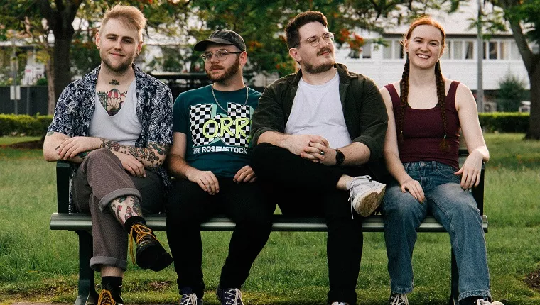 4 persons sitting on a bench in a park