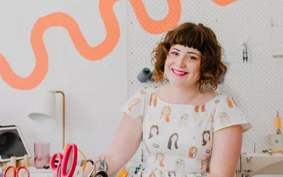 Brunette woman sitting in colourful shop - Alice Nightingale