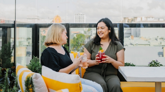 Two females on top of Cielo Rooftop with a cocktail
